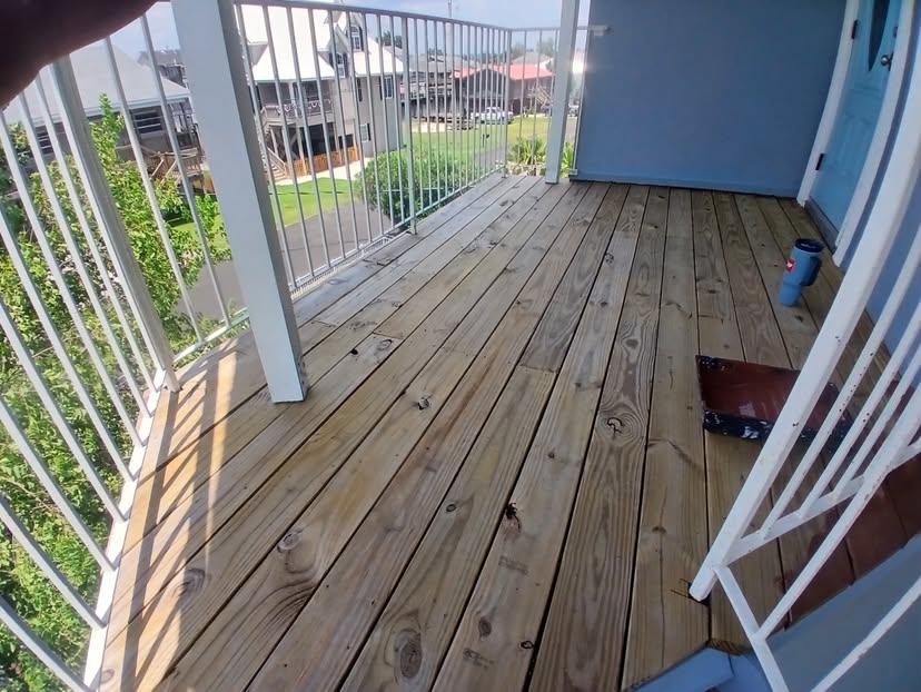 Weathered pressure-treated deck boards on a raised porch before refinishing