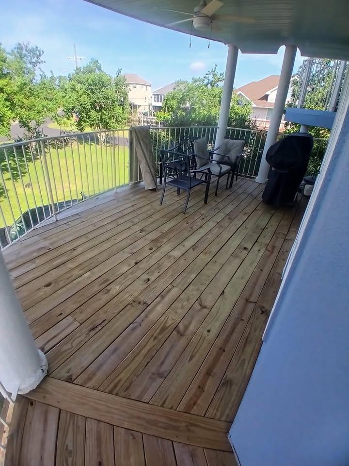 Bare deck boards on a covered porch with patio furniture and a grill