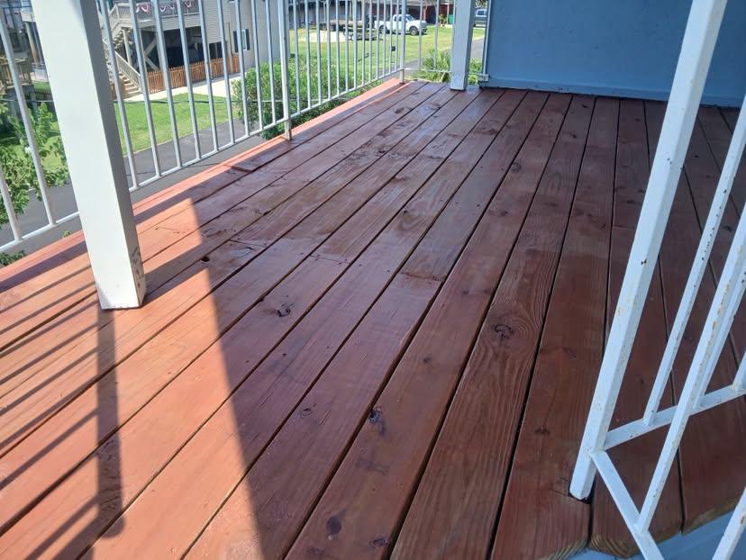 Refinished deck boards meeting a white railing post at a porch corner