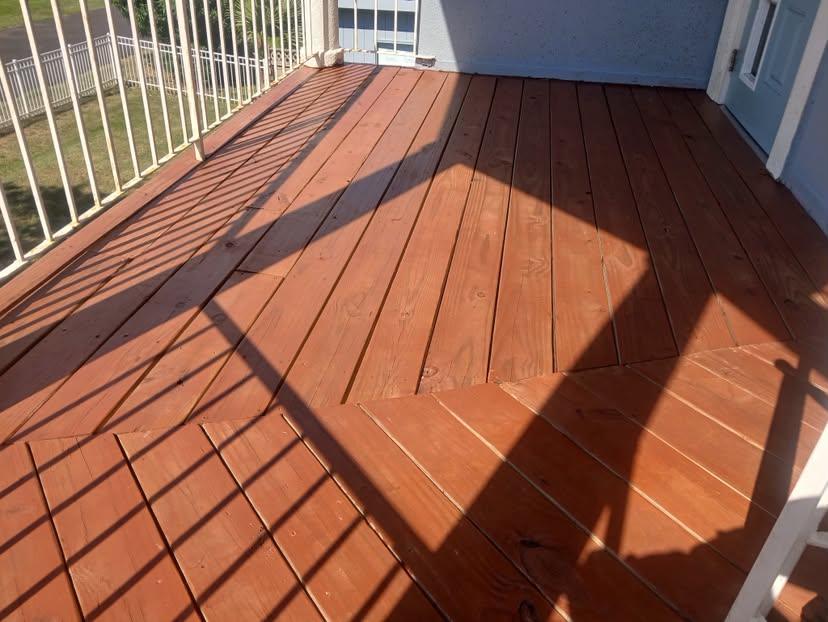 Deck boards refinished in a warm cedar tone on a wraparound porch