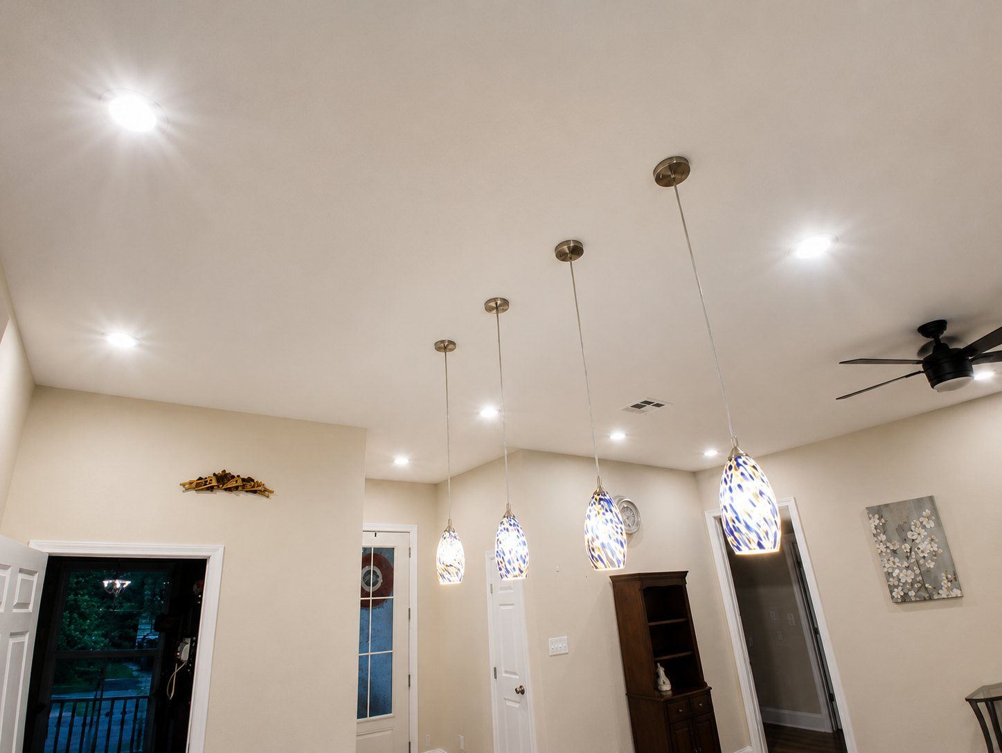 Art-glass pendant lights and recessed cans installed across an open ceiling