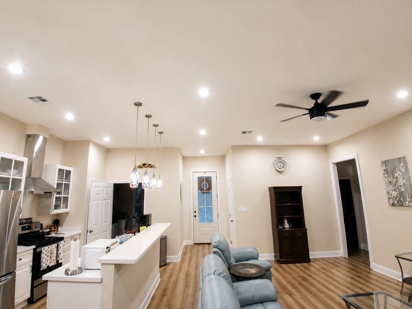 Recessed lighting and art-glass pendants installed over a kitchen breakfast bar