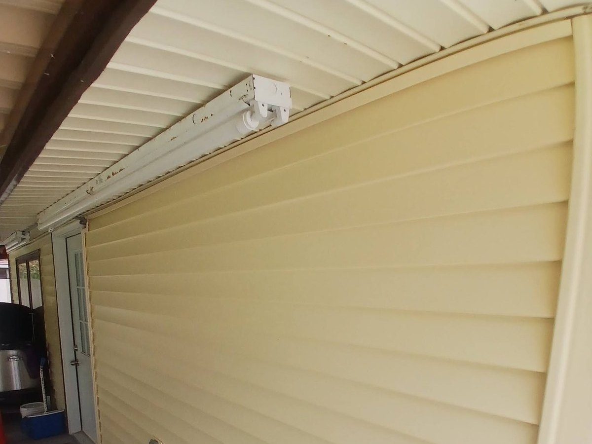 Cream vinyl lap siding installed on a wall beneath a carport